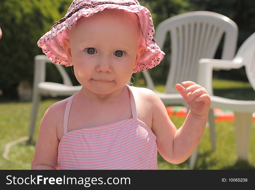 Little baby girl with a funny face in a pink hat. Little baby girl with a funny face in a pink hat