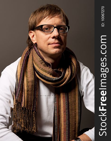 Man in glasses and scarf smiling isolated over gray