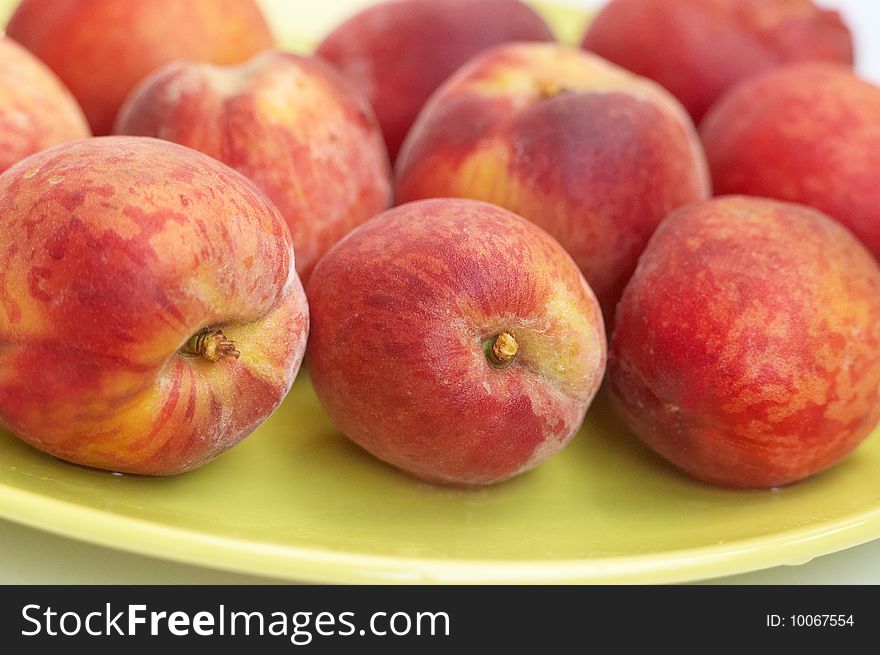 Fresh fruits: red riped peaches on green plate