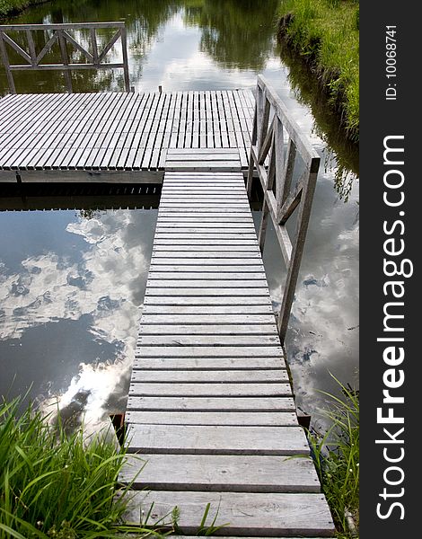 Wooden bridge and reflection of blue sky in water. Wooden bridge and reflection of blue sky in water