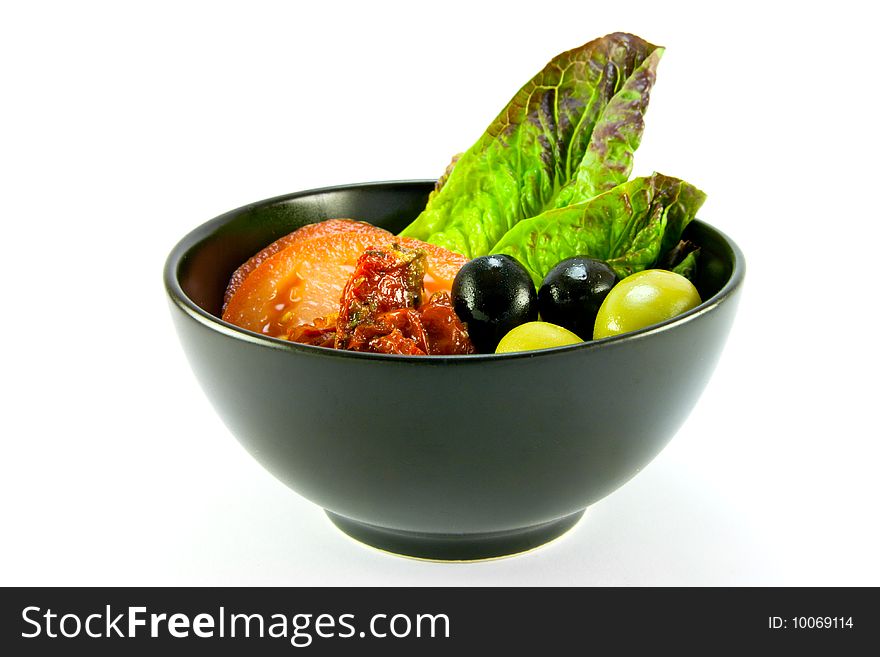 Black bowl with tomatoes, lettace and green and black olives on a white background. Black bowl with tomatoes, lettace and green and black olives on a white background