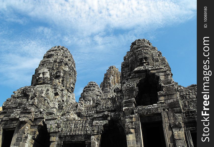 Image of a temple in angkor that has many rock formed faces.
