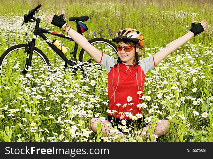 An image of a girl sitting on the grass at the bicycle. An image of a girl sitting on the grass at the bicycle
