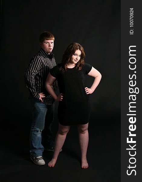 Teenage couple standing together against black background