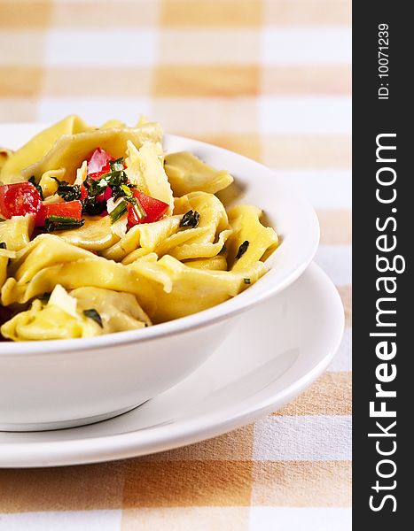 Tortellini primavera garnished with basil leaves on white plate