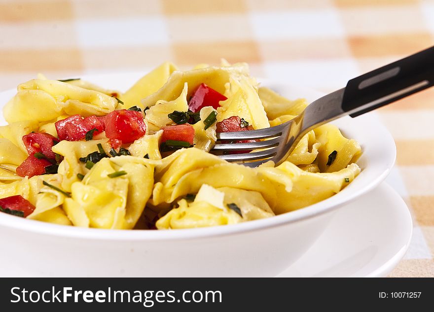 Tortellini primavera garnished with basil leaves on white plate