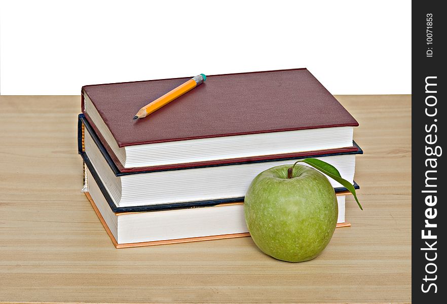 Apple and pencil on top of books