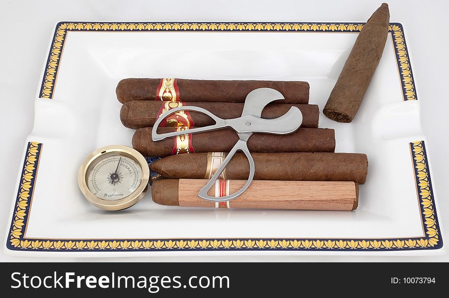 A few cigars, cutters, and hygrometer are in an ashtray