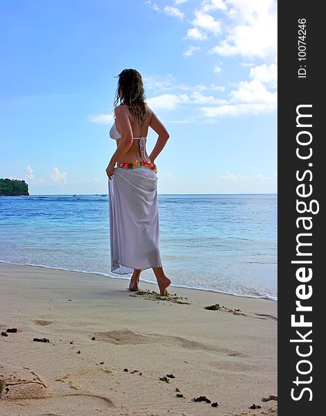 Beautiful brunette with long hair walking along the sand beach on Bali in Indonesia. Beautiful brunette with long hair walking along the sand beach on Bali in Indonesia