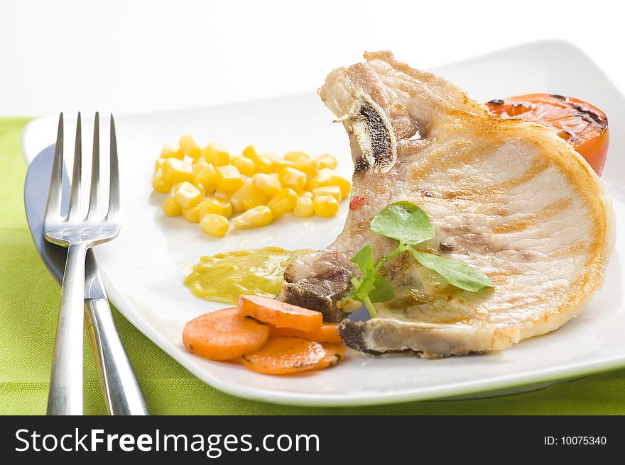 Tasty pork chop with corn carrot tomato isolated