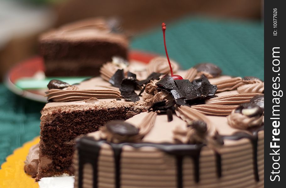 A mocha chocolate cake. A slice was placed at far background. A mocha chocolate cake. A slice was placed at far background.