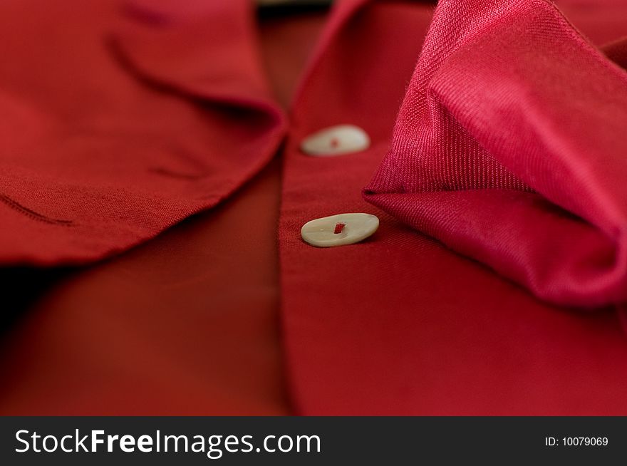 Detail of a red female business suit with a folded sleeve and two pearl buttons. Detail of a red female business suit with a folded sleeve and two pearl buttons