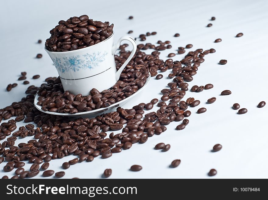 Cup of coffee beans on white background