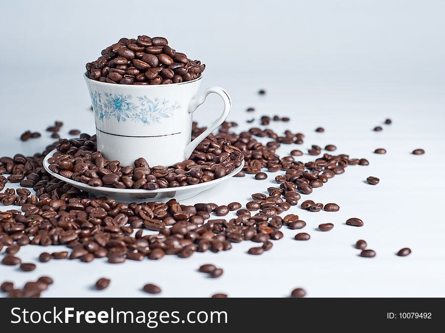 Cup of coffee beans on white background