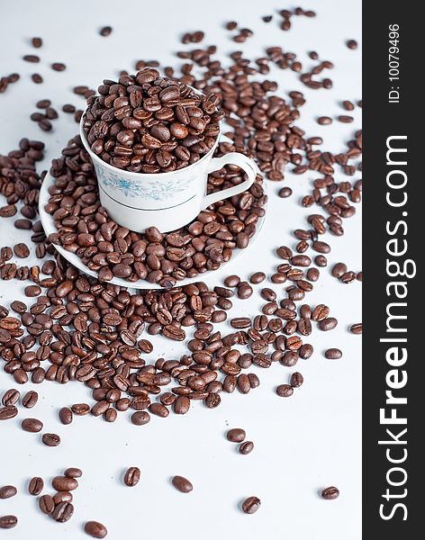 Cup of coffee beans on white background