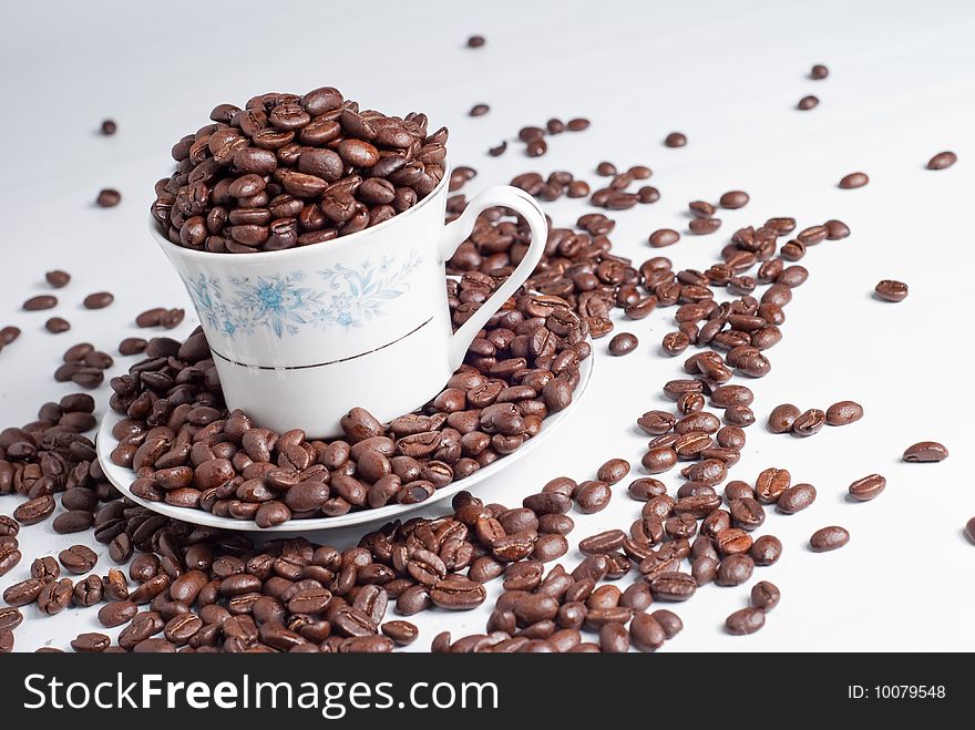 Cup of coffee beans on white background