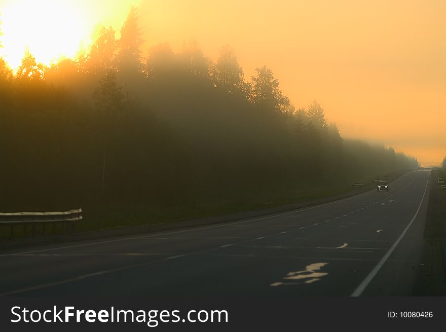 Hazy morning on highway. Lonely car moving along. Sunlights from trees. Hazy morning on highway. Lonely car moving along. Sunlights from trees