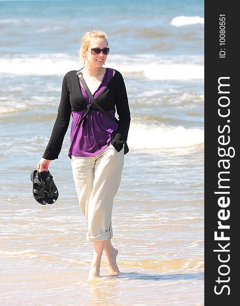 Blond smiling girl walking on the beach