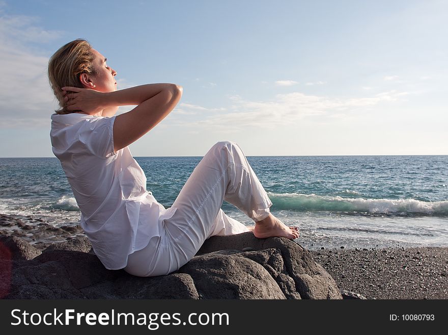 A woman is siting on the beach and relaxing. A woman is siting on the beach and relaxing.