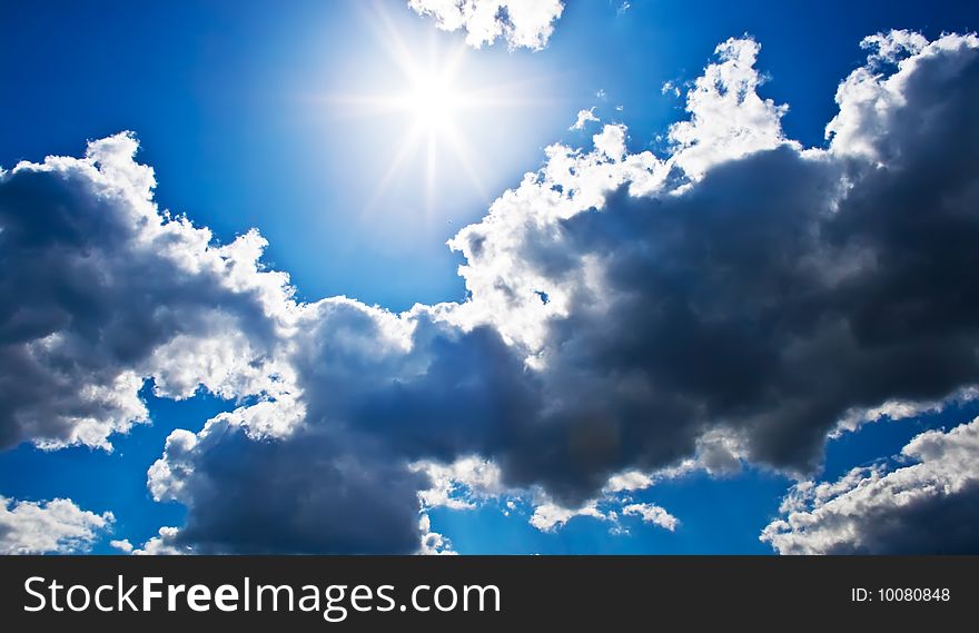 Bright sunrays in a blue cloudy sky