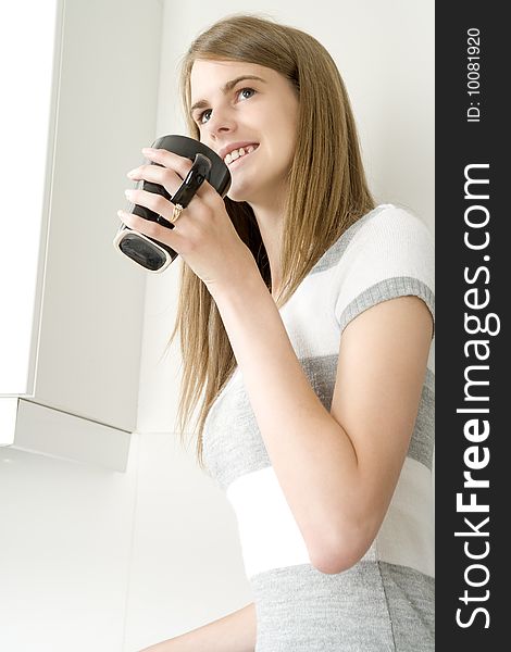 Female model with hot drink in kitchen setting. Female model with hot drink in kitchen setting