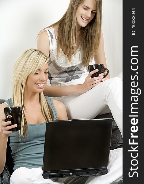 Two female models using laptop and relaxing in lounge setting. Two female models using laptop and relaxing in lounge setting