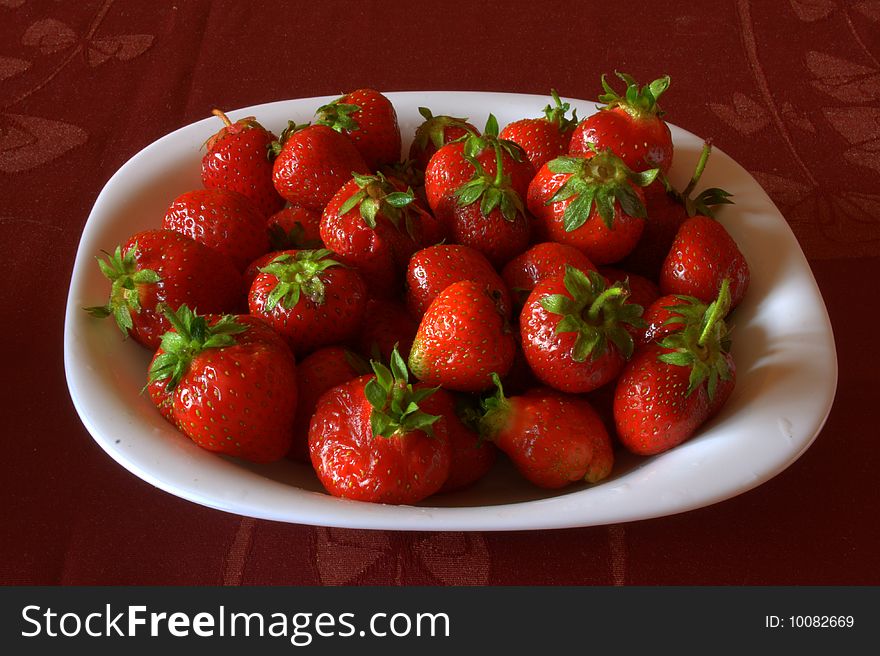 A lot of red strawberries with green leafs.
