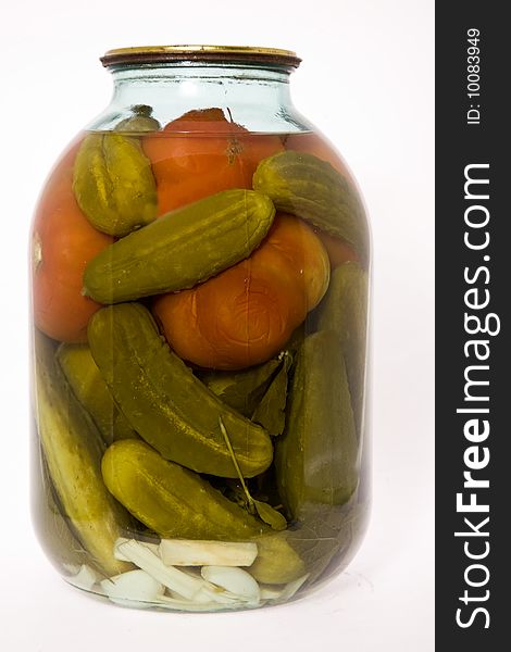 In a glass jar marinaded cucumbers and tomatoes on a white background. In a glass jar marinaded cucumbers and tomatoes on a white background