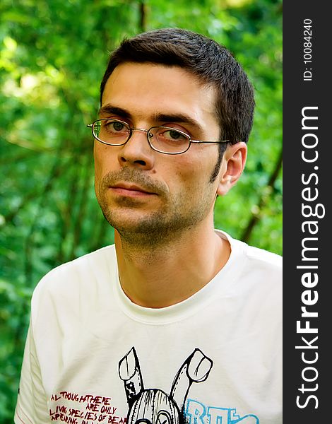 Portrait of young male in glasses and white t-shirt in the forest. Portrait of young male in glasses and white t-shirt in the forest