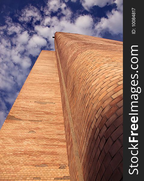 High brick building against the blue sky and clouds