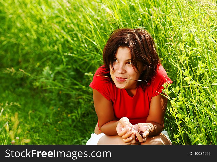 Young beautiful girl with cherries in their hands against a background of grass