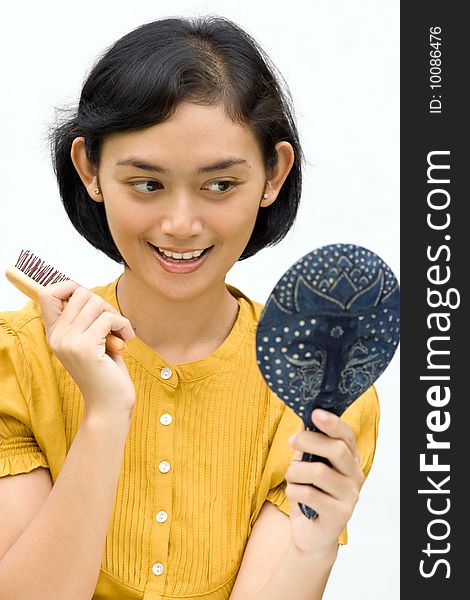 Lifestyle portrait of pretty asian young woman dressing with antique mirror and comb on hands, ready to go out. Lifestyle portrait of pretty asian young woman dressing with antique mirror and comb on hands, ready to go out.