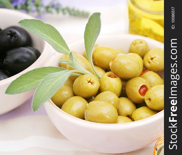 Some green olives in a bowl with sage