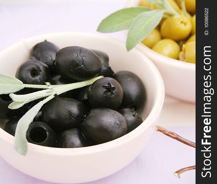 Some black and green olives in 2 bowls. Some black and green olives in 2 bowls