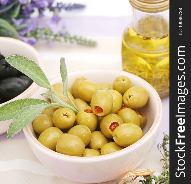 Some green olives in a bowl with sage
