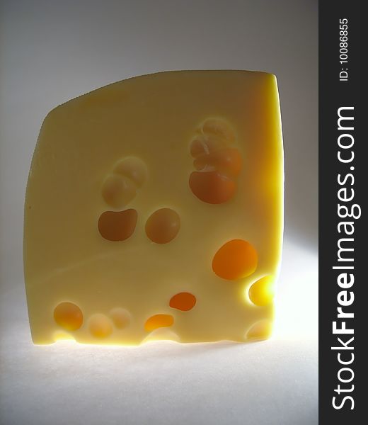 Beautiful piece of cheese with big holes on a grey background