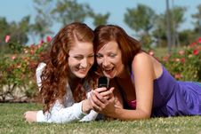 Two Girlfriends With A Mobile Phone In Park Royalty Free Stock Photos