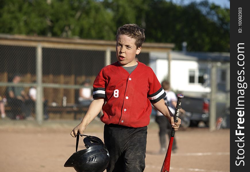 This young boy just struck out and you can see by his facial expression that he is not very happy about that. This young boy just struck out and you can see by his facial expression that he is not very happy about that.