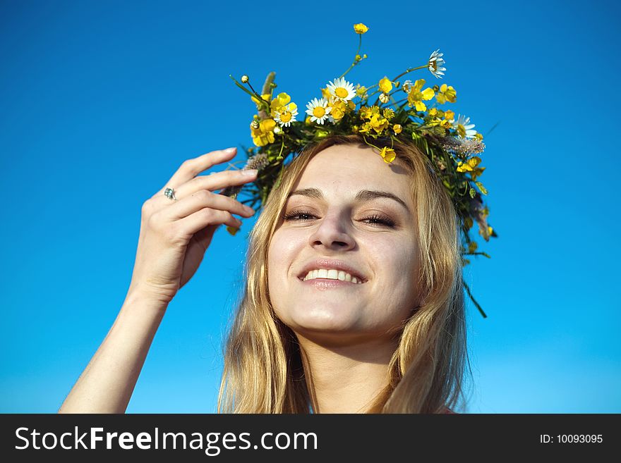 A portrait of a pretty woman in a chaplet of summer flowers