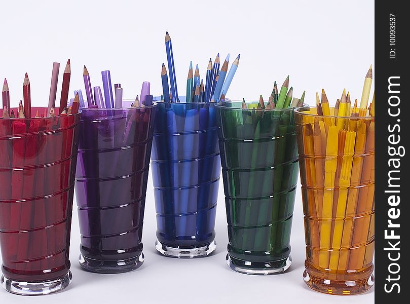 Five drinking glass holding colored drawing pencils and pens. Five drinking glass holding colored drawing pencils and pens.