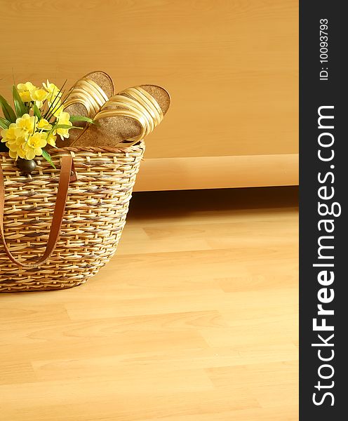 Beach bag with summer footwear and flowers on wooden