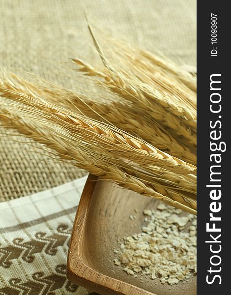 Wheat ears and wooden bowl on sacking. Food background.