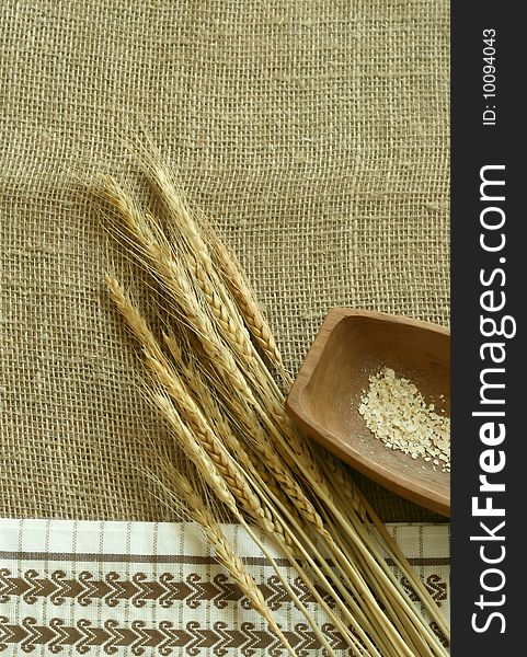 wheat ears, wooden bowl and   kitchen towel on sacking. wheat ears, wooden bowl and   kitchen towel on sacking