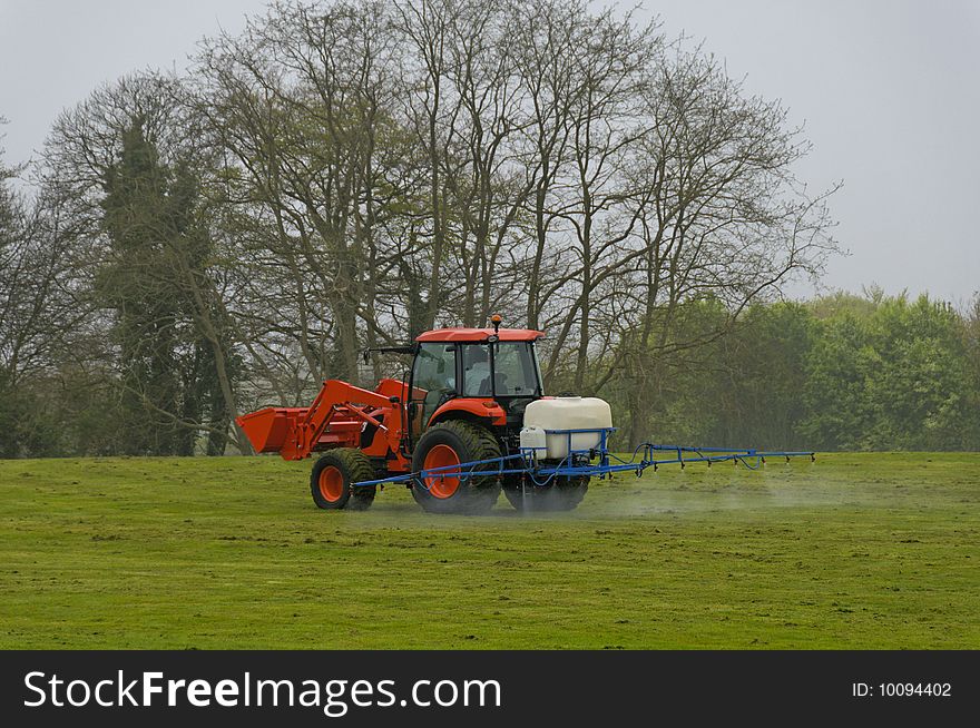 A red tractor spreads of the product on the grass