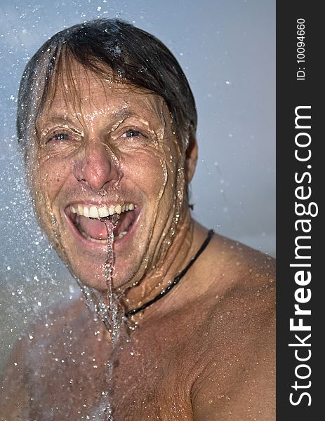 A colour portrait of a happy laughing forties man under a shower outside. A colour portrait of a happy laughing forties man under a shower outside.