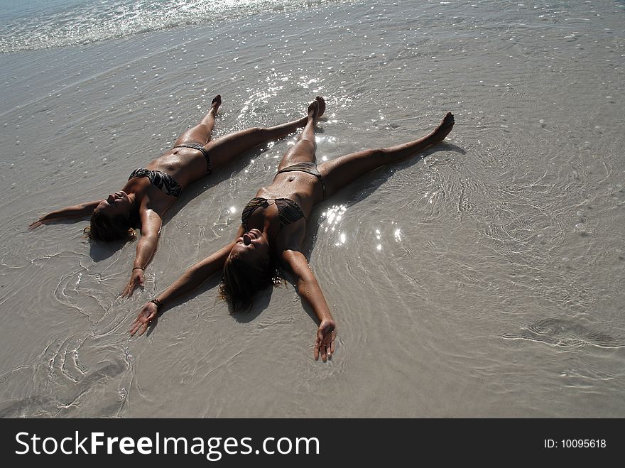 Two sweet teenage girls lying in the water on paradise beach. Two sweet teenage girls lying in the water on paradise beach