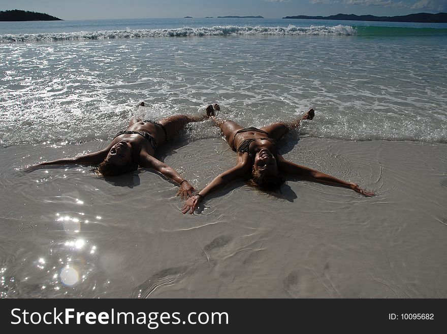 Two teenage girls lying on the beach