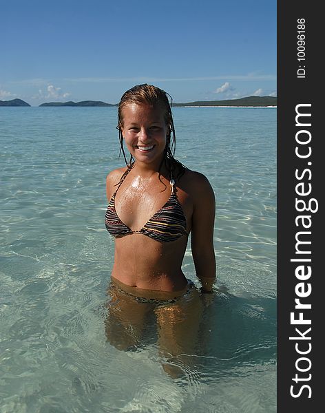 Beautiful young teenage girl standing in water at paradise beach with turquoise water