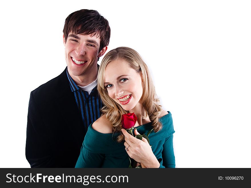 A happy couple smiles at the camera and the girl holds a red rose. A happy couple smiles at the camera and the girl holds a red rose