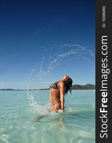 Beautiful young teenage girl flicking hair in turquoise blue water at paradise beach